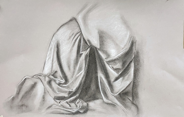 Disegno di un panneggio a carboncino con chiari e scuri su sfondo beige