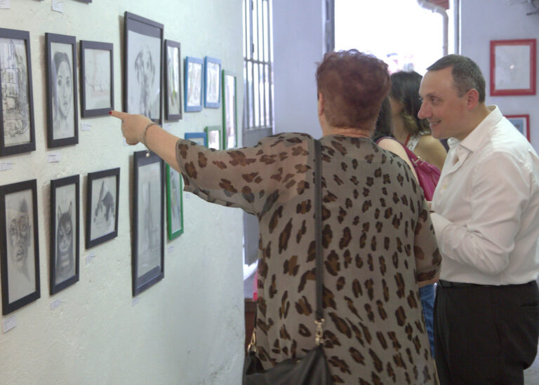 Una coppia ammira opere create dai bambini, esposte alla mostra di fine anno